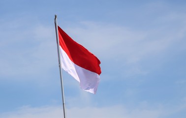 Indonesian red and white flag fluttering in the blue sky