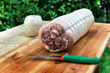 Chopping board with raw porchetta roast rolled pork