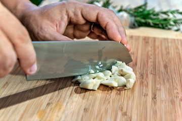 Chopping garlic with knife on cutting board