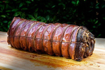 Whole Cooked roasted rolled pork on chopping board