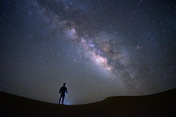Naklejka na ściany i meble Milky way galaxy with a man standing and watching at Tar desert, Jaisalmer, India. Astro photography.