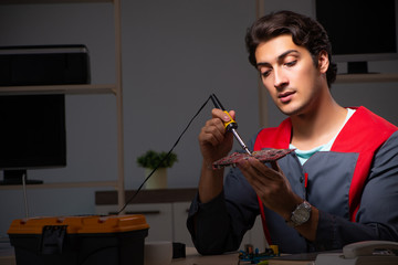 Young handsome repairman repairing computer 