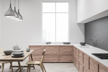 Fototapeta na wymiar White and gray kitchen with table, side view