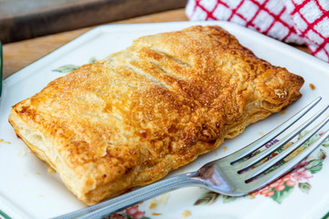 Close-up of Home-made Apple Turnover on a side plate, with a red ad white tea towel in the background