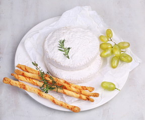 Camembert with a bunch of white grapes and grissini sticks
