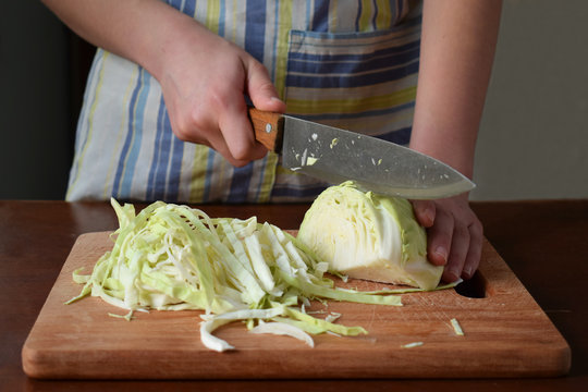 Woman cook sauerkraut or salad on wooden background. Step 1 - Chop Cabbage. Fermented preserved vegetables food concept.
