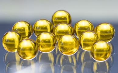 Yellow and orange medicine capsules containing fish oil, omega 3