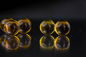 Yellow and orange medicine capsules containing fish oil, omega 3