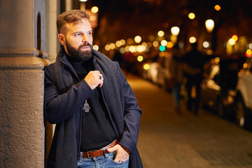 Hombre joven con barba y elegante en la calle, en una noche de invierno