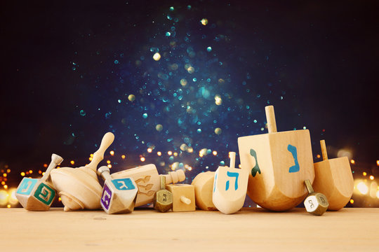 Banner of jewish holiday Hanukkah with wooden dreidels (spinning top) over glitter shiny background.