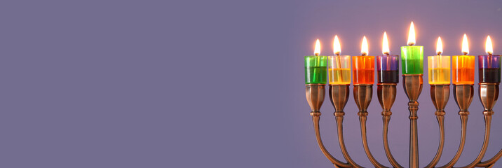 image of jewish holiday Hanukkah background with menorah (traditional candelabra) and colorful oil candles.