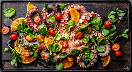 Fototapeta na wymiar Whole octopus salad with orange, tomatoes and cress salad served on board with wine
