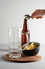 Glass and lager beer bottle with potato chips on gray concrete background. Close up view with copy...