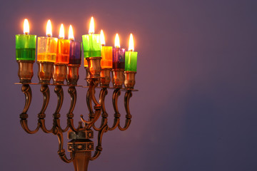 image of jewish holiday Hanukkah background with menorah (traditional candelabra) and colorful oil candles.