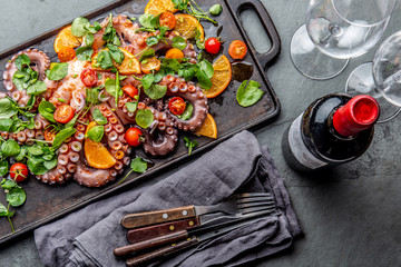 Whole octopus salad with orange, tomatoes and cress salad served on board with wine © lblinova