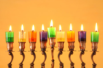 Fototapeta premium image of jewish holiday Hanukkah background with menorah (traditional candelabra) and colorful oil candles.