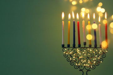 image of jewish holiday Hanukkah background with menorah (traditional candelabra) and colorful oil candles.