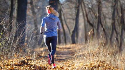 Back view of running girl in autumn park.