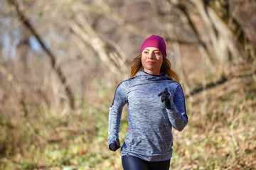 Young woman jogging on trail in autumn park