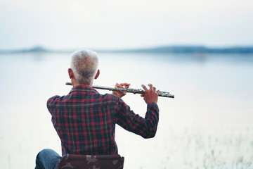 Old man playing flute with nature background