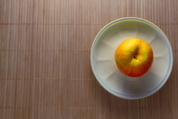 Red and yellow apple on white plate. Kitchen, lunch.