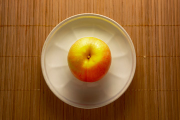 Red yellow apple on a white plate