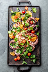 Whole octopus salad with orange, tomatoes and cress salad served on board with wine