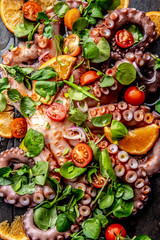 Whole octopus salad with orange, tomatoes and cress salad served on board with wine