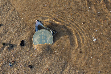 Bitcoin M&uuml;nze in Muschel am Strand