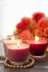 Burning candles with rose flowers bouquet on gray table, close up home interior details