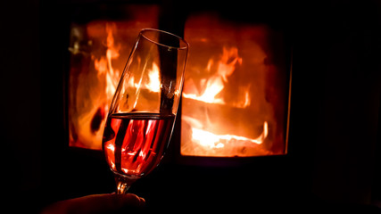 Glass of champagne on the background of a burning fireplace in the dark. Romantic evening.