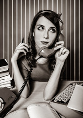 young woman as secretary at her desk near the typewriter and dial phone. 60-s style. Image in black...