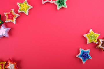 Fototapeta na wymiar Christmas New Year star stars different colors made from beads handmade on red pink background