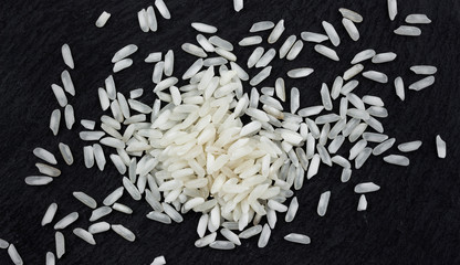 Heap of rice grains on black background. Top view