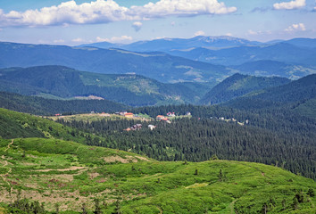 Naklejka na ściany i meble Green fir trees and houses of the village against the background of the Carpathian mountains in the summer. Dragobrat, Ukraine.Travel adventure and hiking activity lifestyle on family summer vacation
