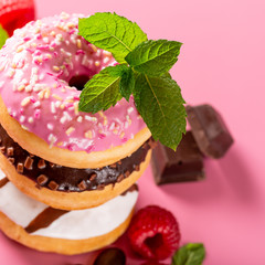 Stack of colorful donuts on pink background. Party food concept.
