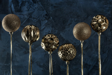 Copy space on a textured dark blue background. Six golden Christmas balls turned upside down....