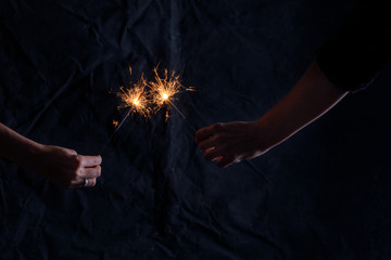 The symbol of the holiday is Bengal lights in hands on a dark minimalist background. Hands with sparklers.