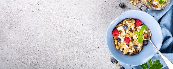 Healthy food background with homemade oatmeal granola or muesli with yogurt and fresh berries for healthy morning breakfast, top view, copy space. Banner.