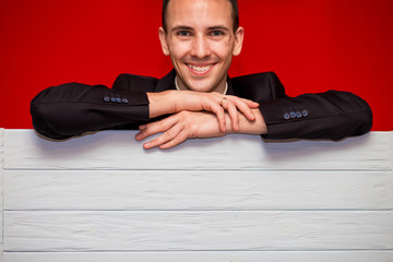 Young smiling man with blank red sign board. Handsome businessman holding banner with copyspace for...