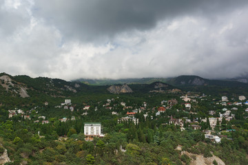Fototapeta na wymiar Landscape view from the rock Diva on the resort village Simeiz. Over the tops of the mountains hanging rain clouds