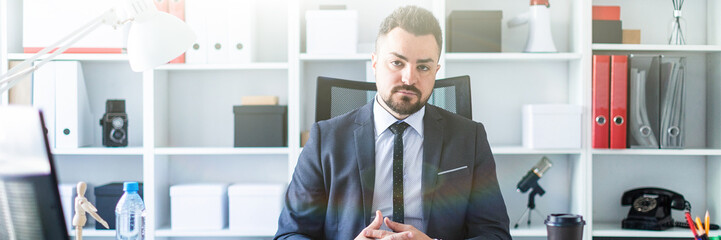 A man is sitting in a chair in the office at the table.