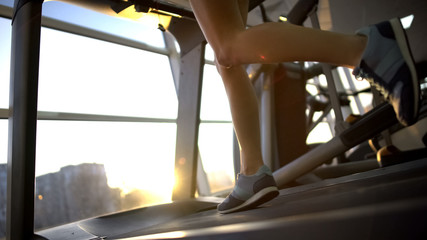 Fototapeta na wymiar Female legs running on gym treadmill, sport woman warming up before workout
