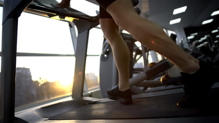 Sportsman running on treadmill in gym, warming up before workout, healthcare