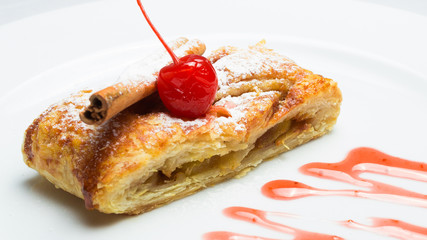 sweet strudel with berries and filling on a white plate