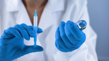 Clinic nurse in medical gloves holding injection syringe, immunization program
