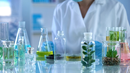 Scientist looking at liquid herbal extracts in bottle, organic perfumery testing - obrazy, fototapety, plakaty