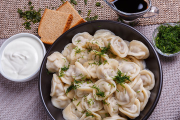 boiled dumplings national dish of many nations with sour cream, soy sauce and greens on the table