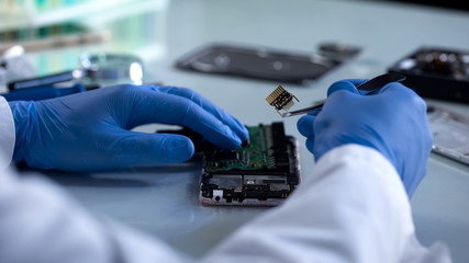 Technician holding computer part with lancet, computer safety, it industry