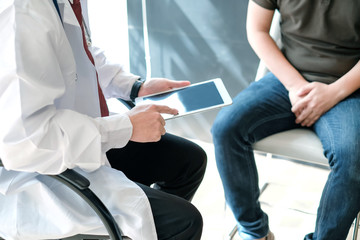Doctor holding digital tablet talk and explain about the treatment of male patients. Treating patients with prostate cancer. - obrazy, fototapety, plakaty